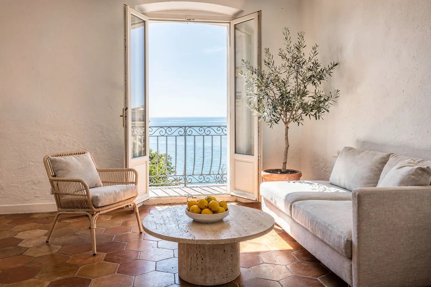 Séjour lumineux d’un appartement à Nice, fenêtres ouvertes sur la mer